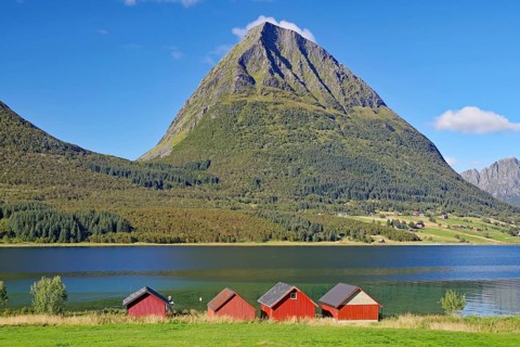 Steep mountains and red wooden sheds on the shore of a fjord, Aldersund, FV 17, Kystriksveien,