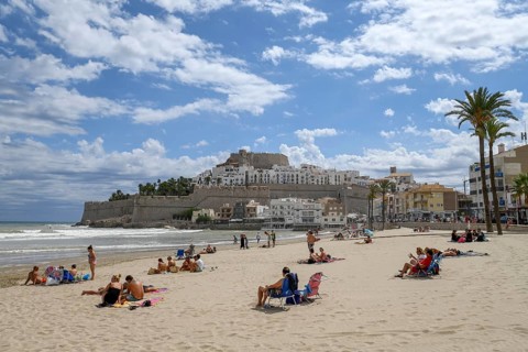 Tourists on the beach, in the background the old town with the Romanesque castle from the 14th