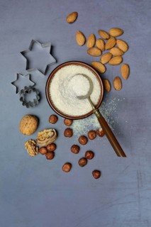 Grated coconut in a bowl and spoon, various nuts and cookie cutters