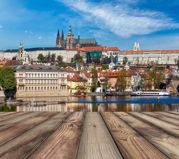Wooden planks vith view of Prague Charles bridge over Vltava river and Gradchany (Prague Castle)