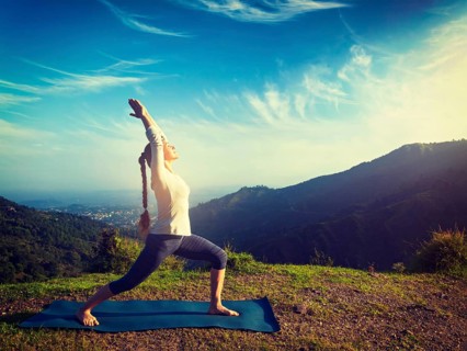 Yoga outdoors, sporty fit woman doing yoga asana Virabhadrasana 1, Warrior pose posture outdoors in