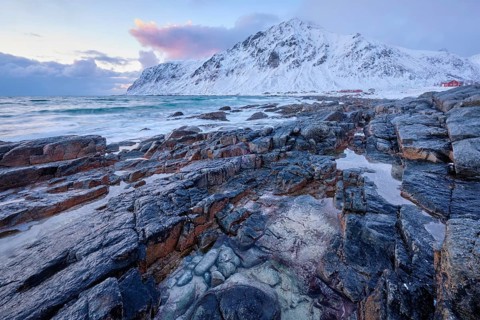 Beach of Norwegian sea on rocky coast in fjord on sunset in winter. Vareid beach, Lofoten islands,