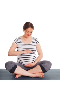 Pregnancy yoga exercise, pregnant woman doing asana Sukhasana easy yoga pose embracing her belly