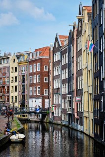 AMSTERDAM, NETHERLANDS, MAY 7, 2017: Amsterdam canal with boat, bridge and old houses with Gay