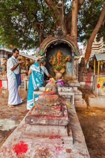 MADURAI, INDIA, FEBRUARY 16, 2013: Indian pilgrim family worshipping Hindu god Ganesh in famous