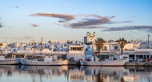 View of Naoussa, Fishing boats in the harbour at sunset, reflected in the sea, White Cycladic