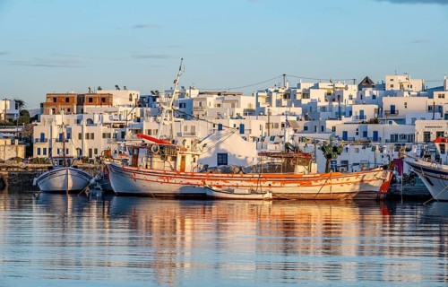 View of Naoussa, Fishing boats in the harbour at sunset, reflected in the sea, White Cycladic