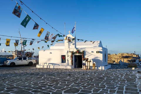 White Cycladic Greek Orthodox Church of Agios Nikolaos, decorated with flags, harbour of Naoussa,