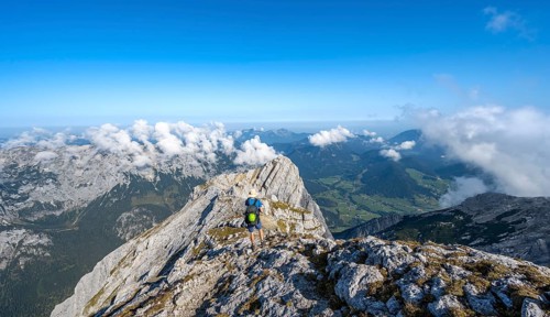Mountaineer on a rocky narrow mountain path with mountain panorama, mountain tour to the summit of