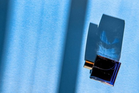 Bottle of perfume for men on blue background under sun light from the window