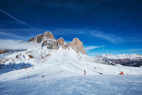 View of a ski resort piste with people skiing in Dolomites in Italy