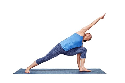 Young fit woman doing Ashtanga Vinyasa Yoga asana Utthita parsvakonasana, extended side angle pose