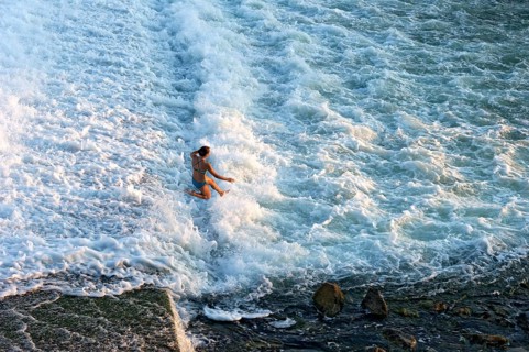 Girl bathing in the spray of the Lech weir, jumping into the white foaming water of the cascades,