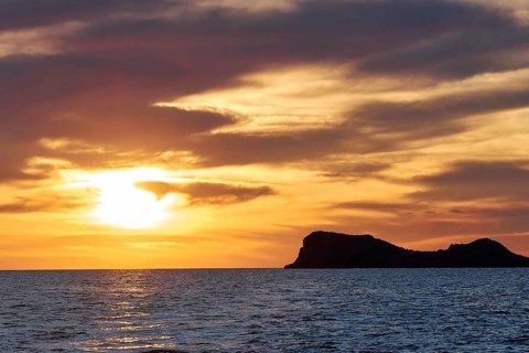 Black rocky coast orange hillem, grey clouds, sunset, dusk, Marettimo, Egadi Islands, Sicily,