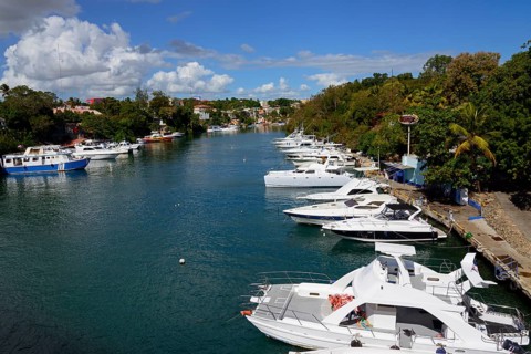 Sunny view of a marina with white yachts and a coastal town, boats on the Dulce River, La Romana,