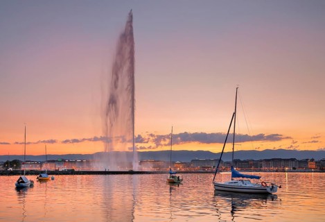 The Jet d'eau at dusk is the landmark in the Lake Geneva basin, with sailboats in the foreground