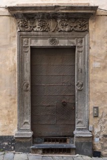 Historic entrance door with decorative floral reliefs on the frame in the historic city centre,