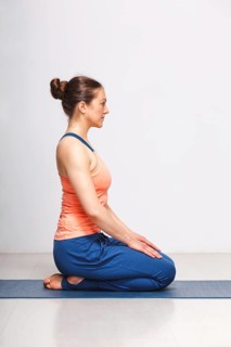 Woman in Hatha yoga asana Vajrasana, vajra pose or diamond pose on yoga mat on yoga mat in studio