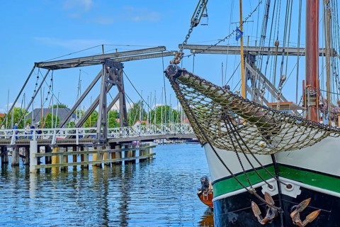Bowsprit and bow of a sailing ship against the picturesque backdrop of Greifswald Wieck town