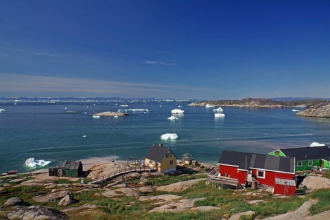 Simple, colourful houses on the edge of a bay covered with icebergs, Ilulissat, Arctic, Disko Bay,