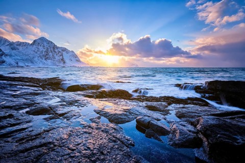 Beach of Norwegian sea on rocky coast in fjord on sunset in winter. Vareid beach, Lofoten islands,