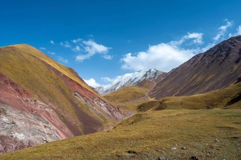 Valley with mountain stream between high mountains in autumn, mountain landscape with glaciated