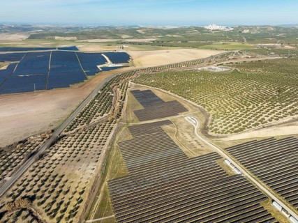 Rows of solar panels at a photovoltaic plant and the town of Espejo in the distance, aerial view,