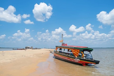 Wooden tourist boat, sightseeing boat beached on Braamspunt, sandbar on the Suriname River, where