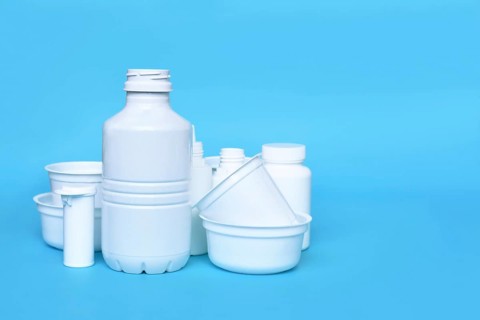 Different empty plastic waste packages on blue background with negative space