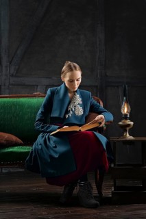 Attractive lady in oldfashioned clothes reading ancient book near vintage kerosene lamp