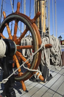 Steering wheel and ropes coiled around belaying pins aboard the Grand Turk, Etoile du Roy, a