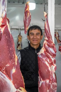 Butcher looking through hung meat, butcher's shop, at the market stall for meat products, Uzgen