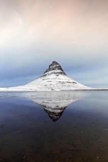 Kirkjufell, nunatak hill covered in snow reflected in water of fjord on the Snæfellsnes peninsula