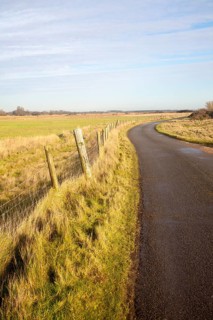 Narrow winding country tarmac road leading into the distance at Shingle Street, Hollesley, Suffolk,