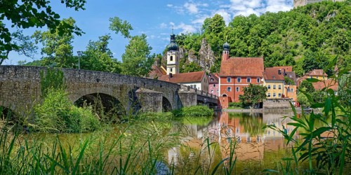 Panoramic view of the ancient stone bridge over the river Naab with the church tower of St Michael