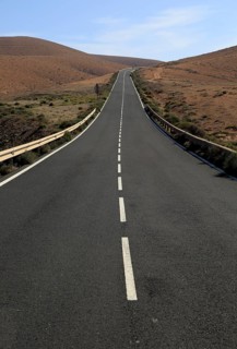 Tarmac road crossing barren desert mountainous land between Pajara and La Pared, Fuerteventura,