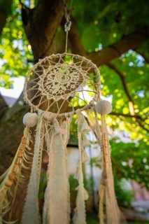 Detailed view of a dreamcatcher hanging from a tree in a well-lit garden, Harz Mountains, Germany,