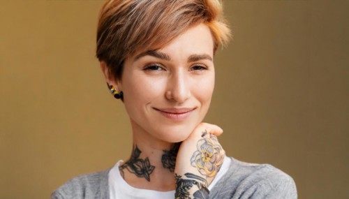 Portrait of a smiling woman with short hair and visible tattoos on a warm-coloured background, AI