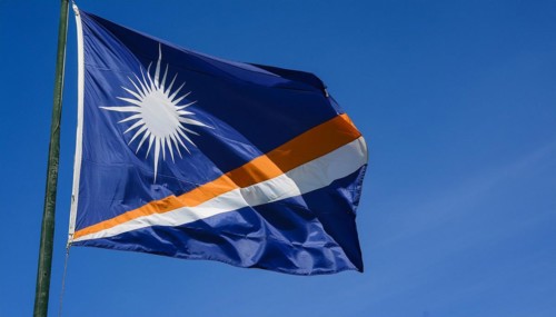 The flag of the Marshall Islands, Pacific Islands, flutters in the wind, isolated against a blue
