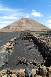 Volcano cone and black volcanic soil farmland, near Tinajo, Lanzarote, Canary Islands, Spain,