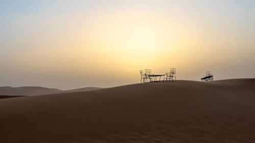 Sunset, cast iron table and chairs in the sand dunes of Erg Chebbi, Sahara, Merzouga, Morocco,