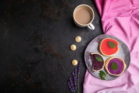 Sweet tartlets with jelly and milk cream with cup of coffee on a black concrete background and pink