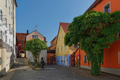 Person riding a bicycle on the Vils alley with historic buildings and cobblestones, Kallmünz, Upper