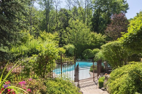 In-ground swimming pool surrounded by copper coloured wrought iron metal security fence and various