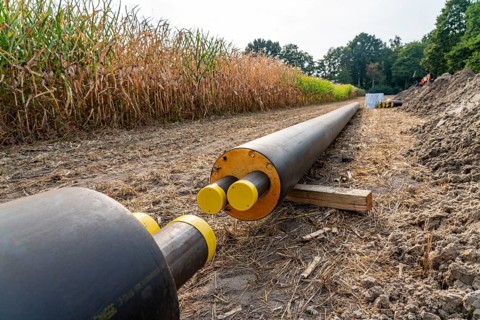 Laying of district heating pipes, next to a field, with maize, the district heating comes from a