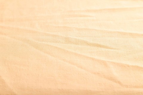 Fragment of smooth orange linen tissue. Side view, natural textile background and texture
