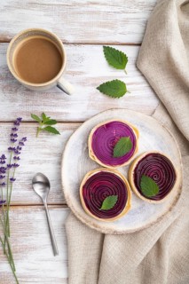 Sweet tartlets with jelly and milk cream with cup of coffee on a white wooden background and linen