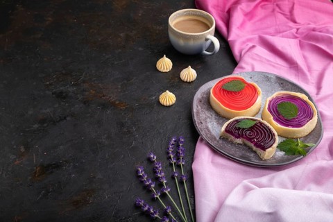 Sweet tartlets with jelly and milk cream with cup of coffee on a black concrete background and pink