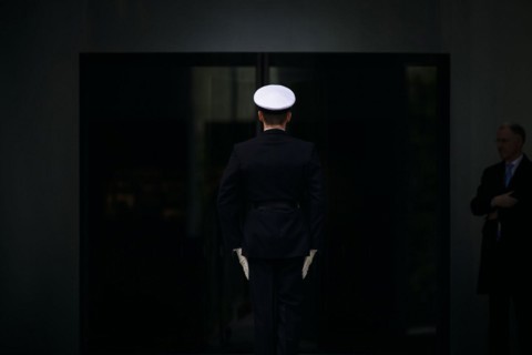 A marine stands with his back to the camera in front of the entrance to the Federal Chancellery.
