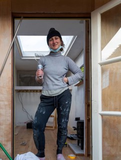 Young woman painting Luton van interior as part of a conversion project, UK